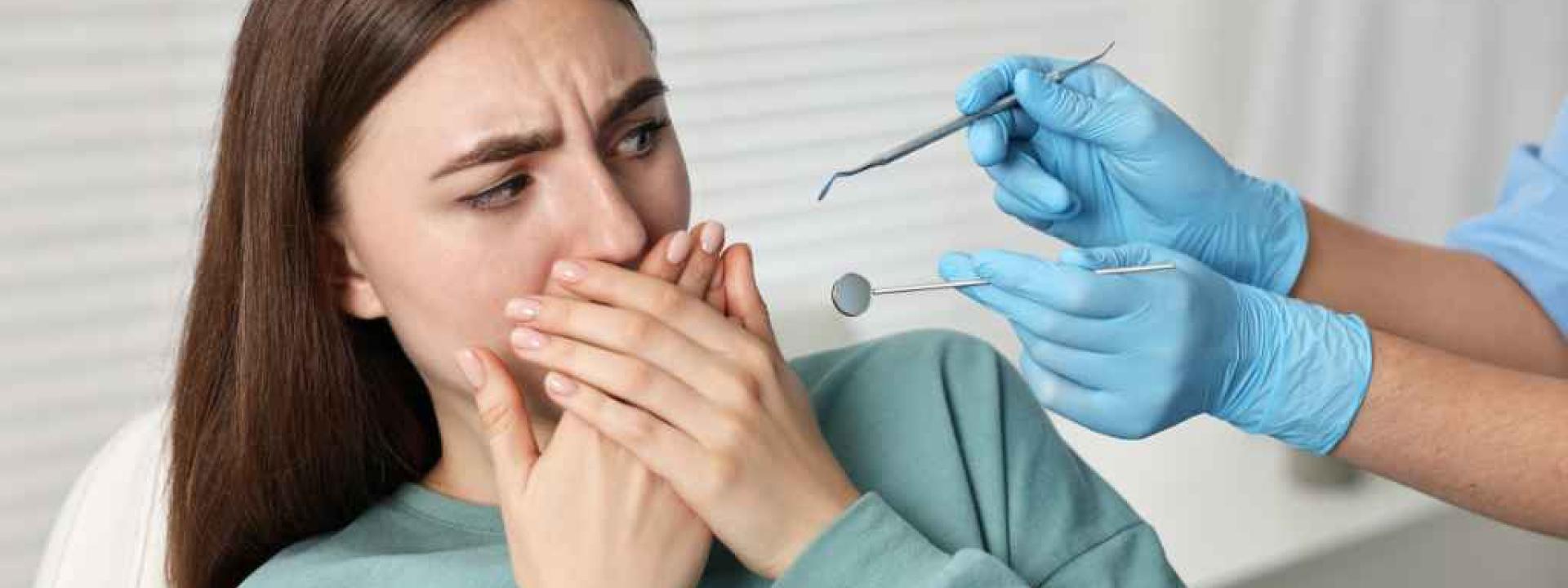 Woman with dental anxiety shying away from dental tools at dentists office